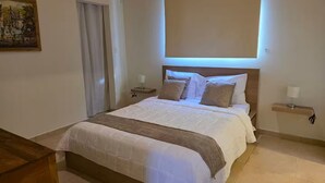 Un dormitorio ordenado con una cama grande, lámparas de noche y un cuadro en la pared.