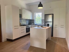 Eine moderne Küche mit weißen Schränken, einer zentralen Kochinsel und einem Edelstahl-Kühlschrank.