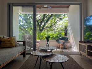 Ein modernes Wohnzimmer mit einer Couch, zwei runden Tischen, einem Sessel und einem Fernseher.