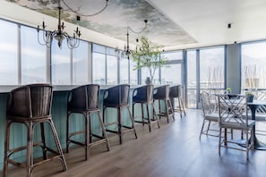 Eine moderne Bar mit Korbartisten, einem Kronleuchter und großen Fenstern mit Blick auf die Stadt.