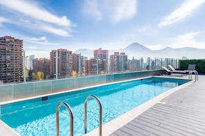 Ein Dachpool mit Blick auf die Stadtlandschaft, darunter Hochhäuser und Berge im Hintergrund.