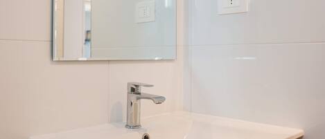 Un baño con un lavamanos blanco, un espejo y un mueble de madera.