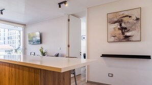 Et moderne køkken med en træø, et fladskærms TV og et stort abstrakt billede på væggen.