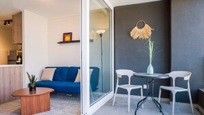 Et moderne opholdsområde med en sofa, et sofabord, et spisebord med stole og en dekorativ vase.