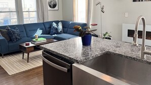 Una cocina moderna con encimera de granito, pileta de acero inoxidable y lavavajillas.
