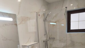 Une salle de bain moderne avec une douche en marbre, un lavabo blanc et des toilettes.