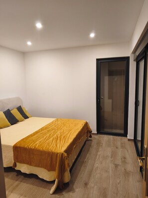 A bedroom with a bed, a door, and a wooden floor. - House with panoramic view near Monaco (Roquebrune-Cap-Martin)
