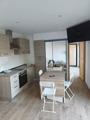 A modern kitchen with a built-in oven, a dining table with chairs, and a view into the adjacent living area. - House with panoramic view near Monaco (Roquebrune-Cap-Martin)