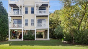 A multi-story residential building with balconies, a covered entrance, and a well-maintained lawn. - Coastal Retreat w/ Balcony, Bikes & Pool Access (New Bern)