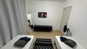 Quarto com duas camas, televisão, porta e espelho.