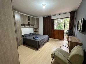 Une chambre à coucher avec un lit, un bureau, une chaise, une armoire et une fenêtre.