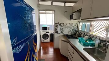 Cozinha com máquina de lavar, painel de azulejos e janela.