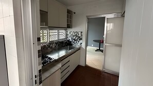 A kitchen with white cabinets, a black countertop, and a tiled backsplash. - Quartos vila olímpia 43 (São Paulo)