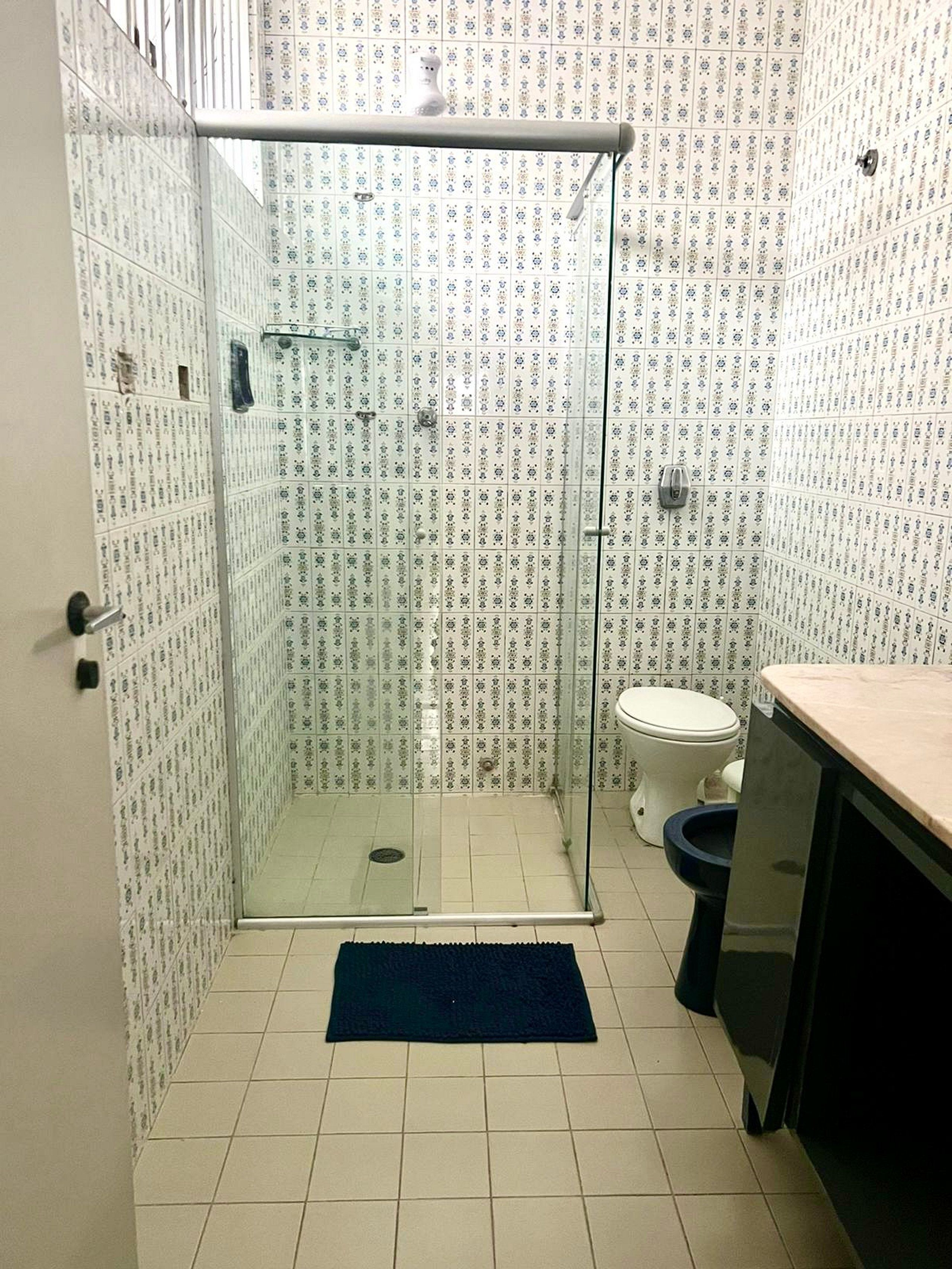 A bathroom with a glass-enclosed shower, a toilet, and a sink.