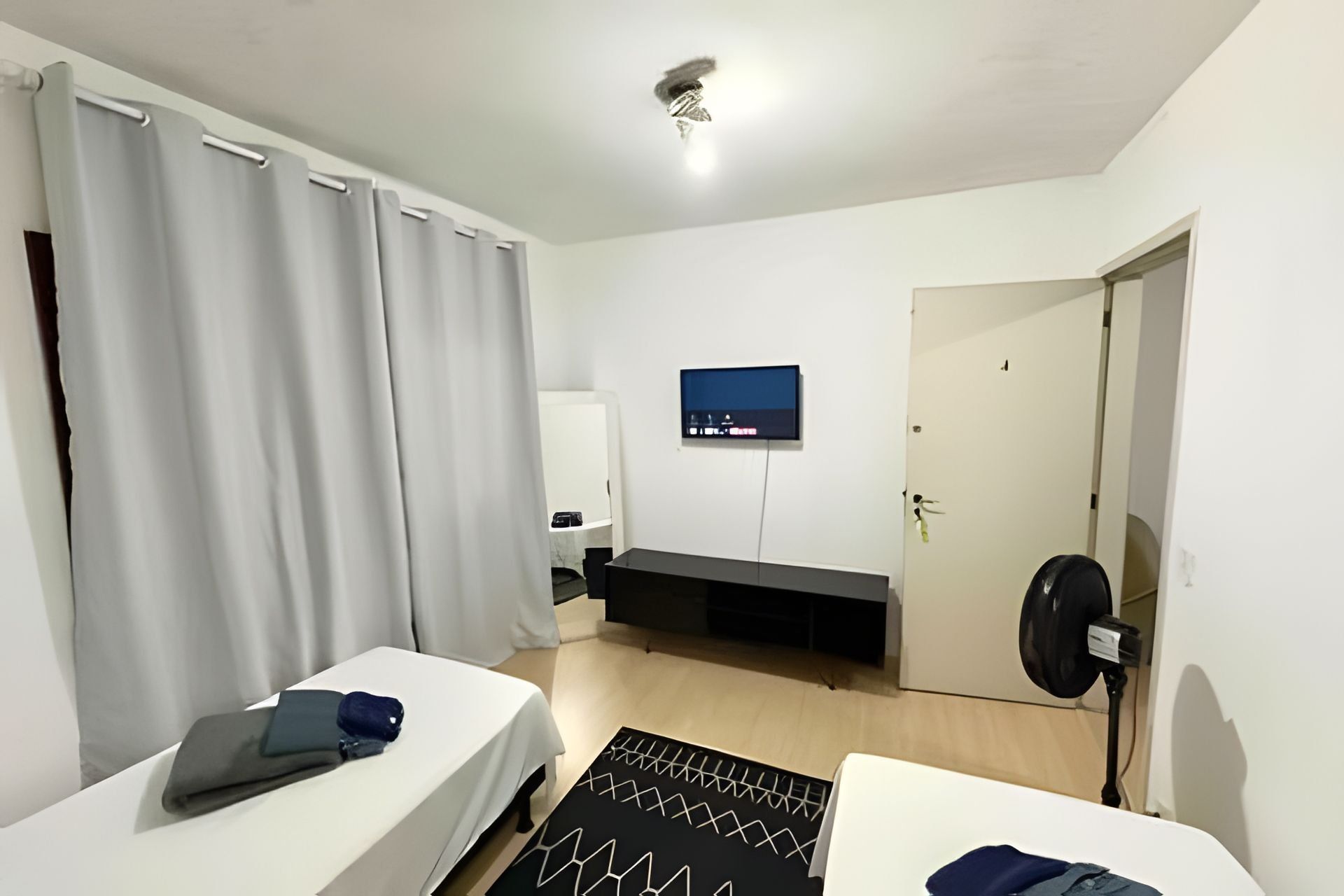 A hotel room with two beds, a TV, a door, and a small table.