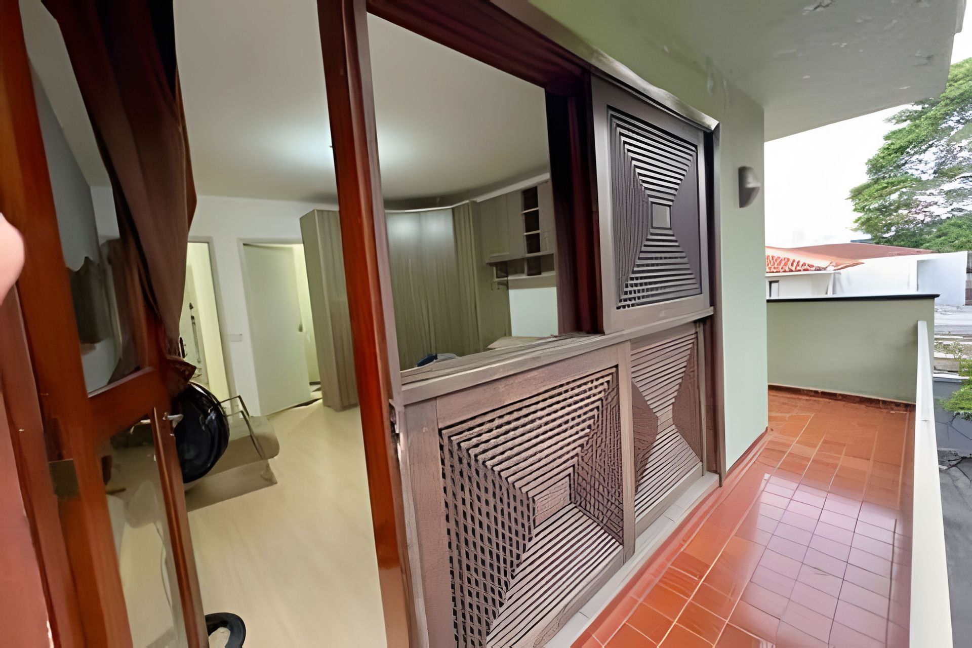 Um quarto com piso de azulejos, uma porta com espelho e uma janela com grade decorativa.