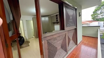 Um quarto com piso de azulejos, uma porta com espelho e uma janela com grade decorativa.