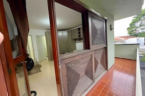 A room with a tiled floor, a door with a mirror, and a window with a decorative grille.