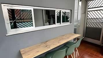 A kitchen with a wooden countertop, green chairs, a window with a view, and a patterned wall.