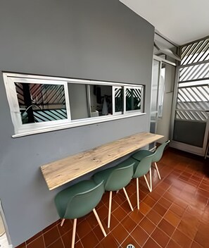 Una cocina con encimera de madera, sillas verdes, ventana con vistas y pared con estampado.