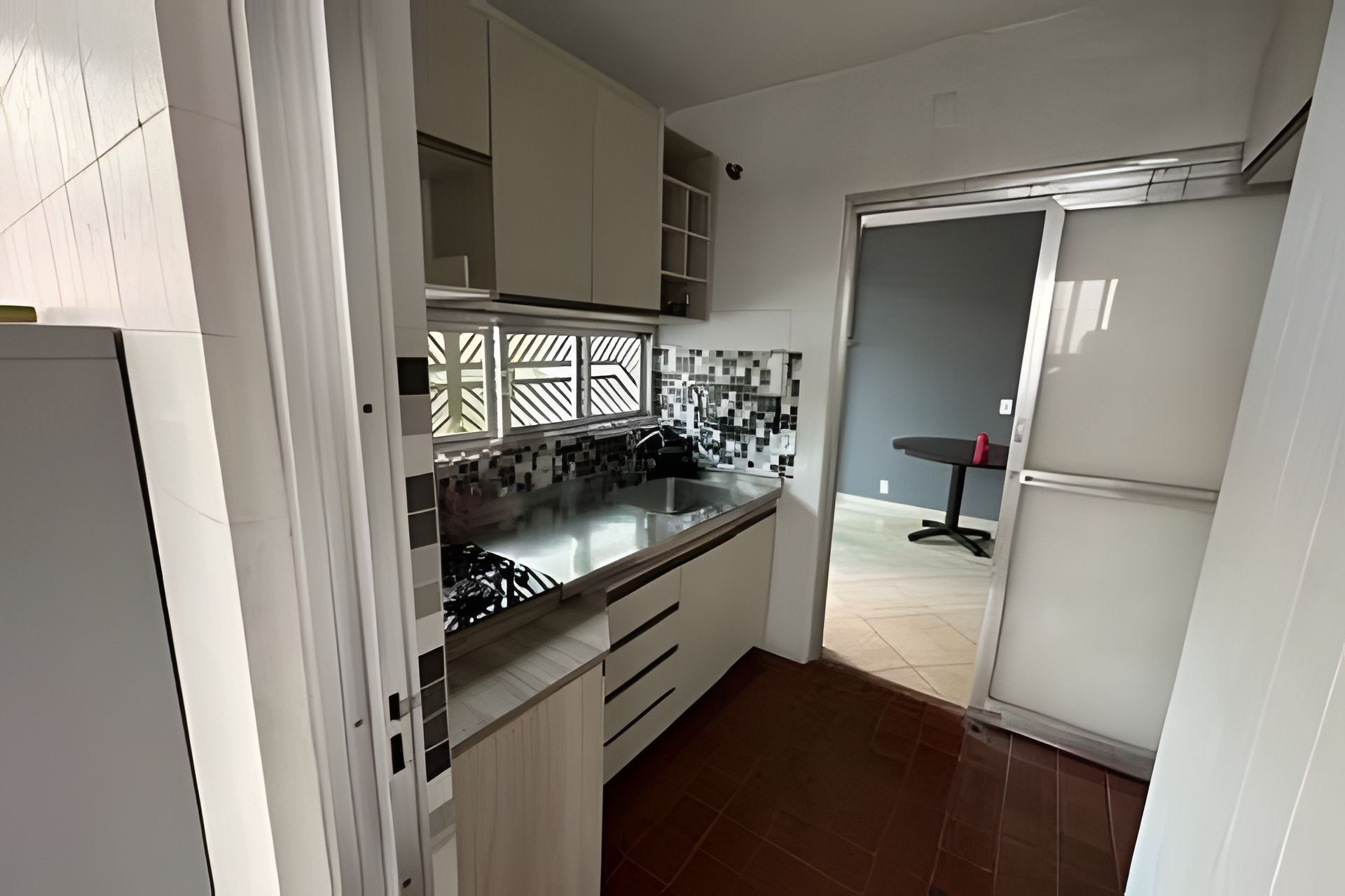 A kitchen with white cabinets, a black countertop, and a tiled backsplash.