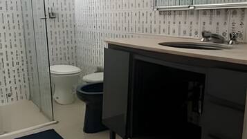 Casa de banho com sanita, lavatório, espelho e zona de duche.