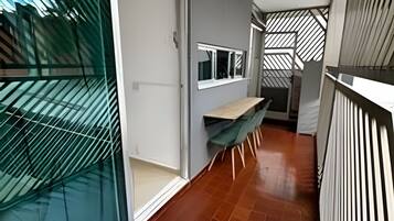 Um corredor com porta de vidro deslizante, uma pequena mesa com cadeiras e parede com padrão.