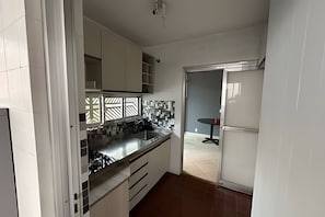 Una cocina con armarios blancos, encimera negra y salpicadero de azulejos.