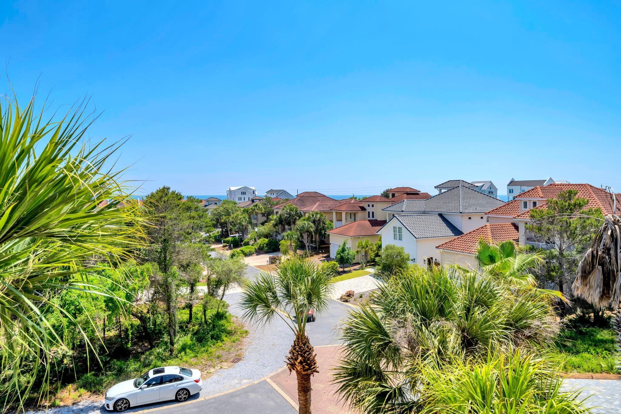 A residential area with houses, a white car, and palm trees.