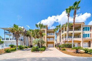 A multi-story hotel with balconies, palm trees, and a clear blue sky. - Casa Valencia (Panama City Beach)