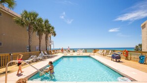 A pool area with clear blue water, lounge chairs, and a view of the ocean. - Casa Valencia (Panama City Beach)