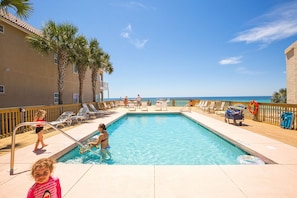 A pool area with clear blue water, lounge chairs, and a view of the ocean. - Casa Valencia (Panama City Beach)