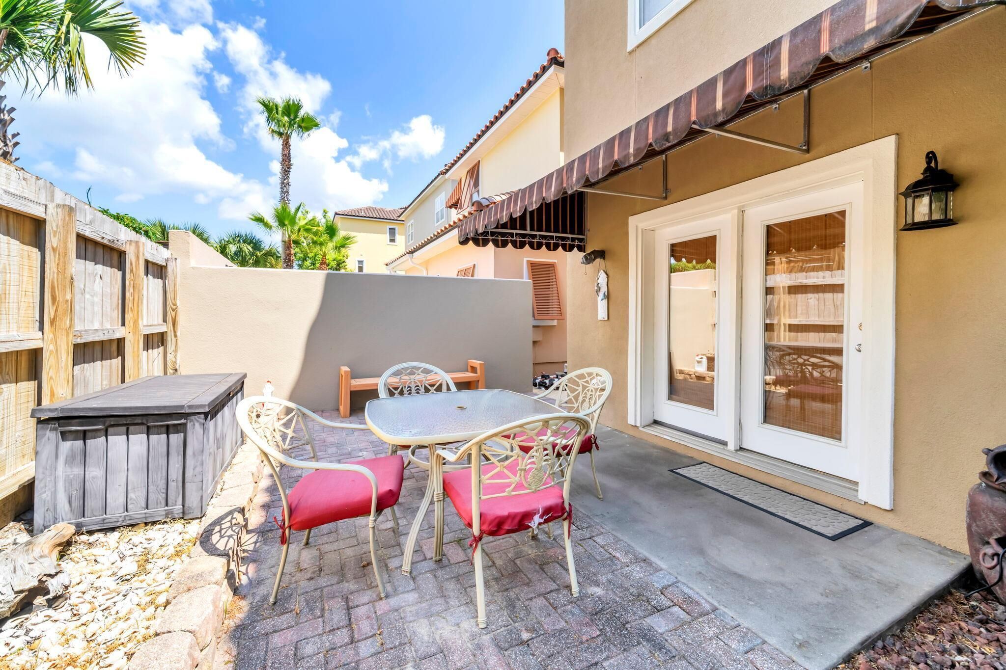 A patio with a table and chairs, a wooden fence, and a building with a tiled roof and a door with glass panels.
