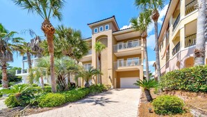 A multi-story hotel with balconies, palm trees, and a paved walkway. - Casa Valencia (Panama City Beach)