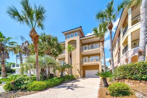 A multi-story hotel with balconies, palm trees, and a paved walkway. - Casa Valencia (Panama City Beach)