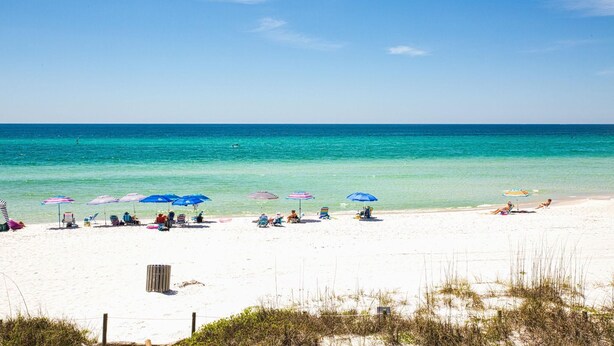 A beach with white sand, clear turquoise water, and several beach umbrellas. - Casa Valencia (Panama City Beach)