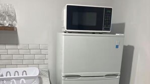 A kitchen with a refrigerator, microwave, and a wine rack.