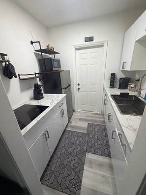 A compact kitchen with a refrigerator, microwave, and coffee maker.