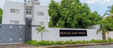 A modern building with a sign reading 'ROYALE JAZZ HOTEL' and a gated entrance.
