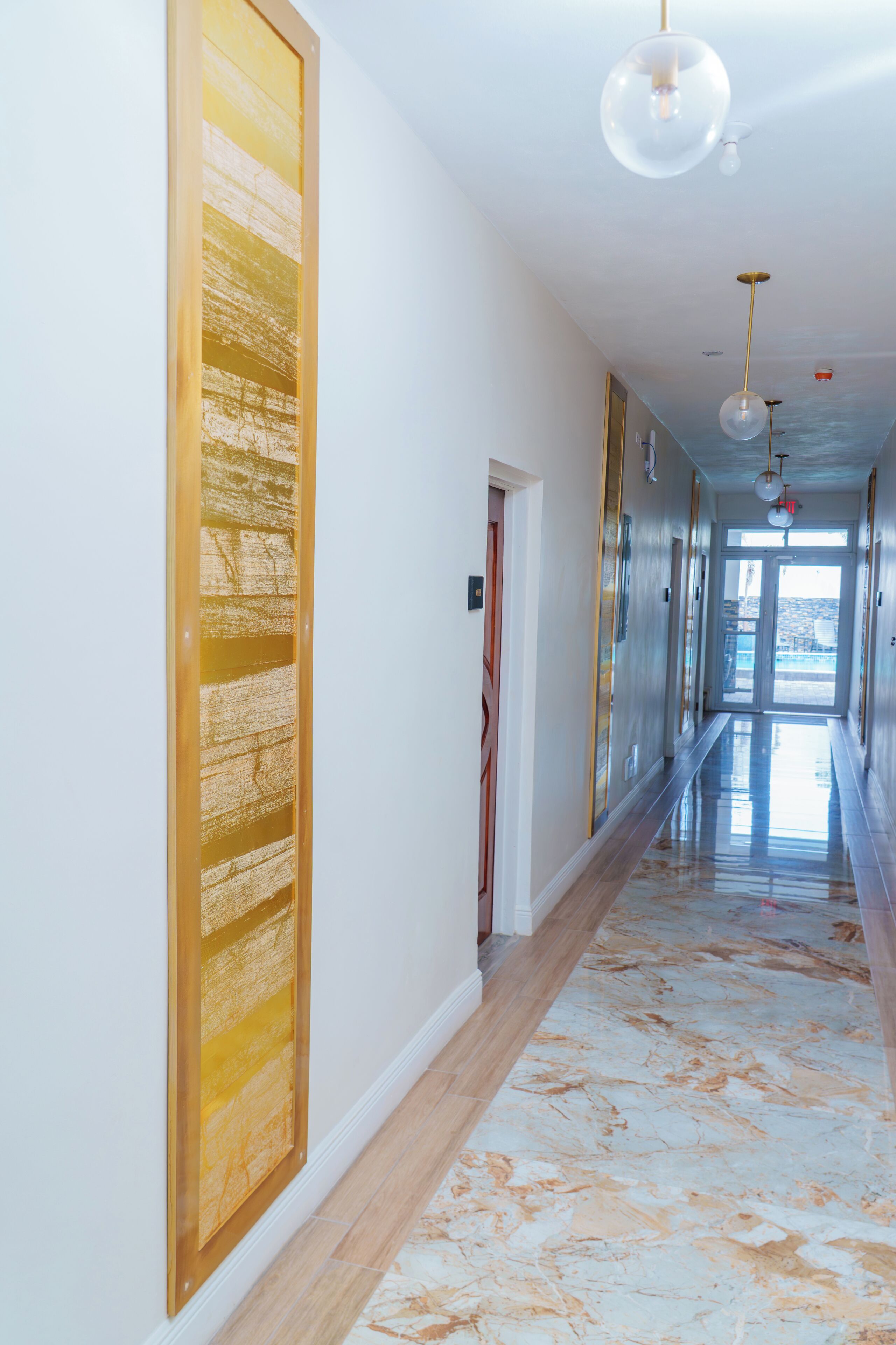 Un pasillo con piso de mármol, paneles de madera e iluminación colgante.