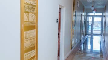 A hallway with a marble floor, wooden paneling, and pendant lighting.