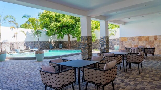 An outdoor patio with a pool, lounge chairs, and tables. - Royale Jazz Hotel (Kingston)