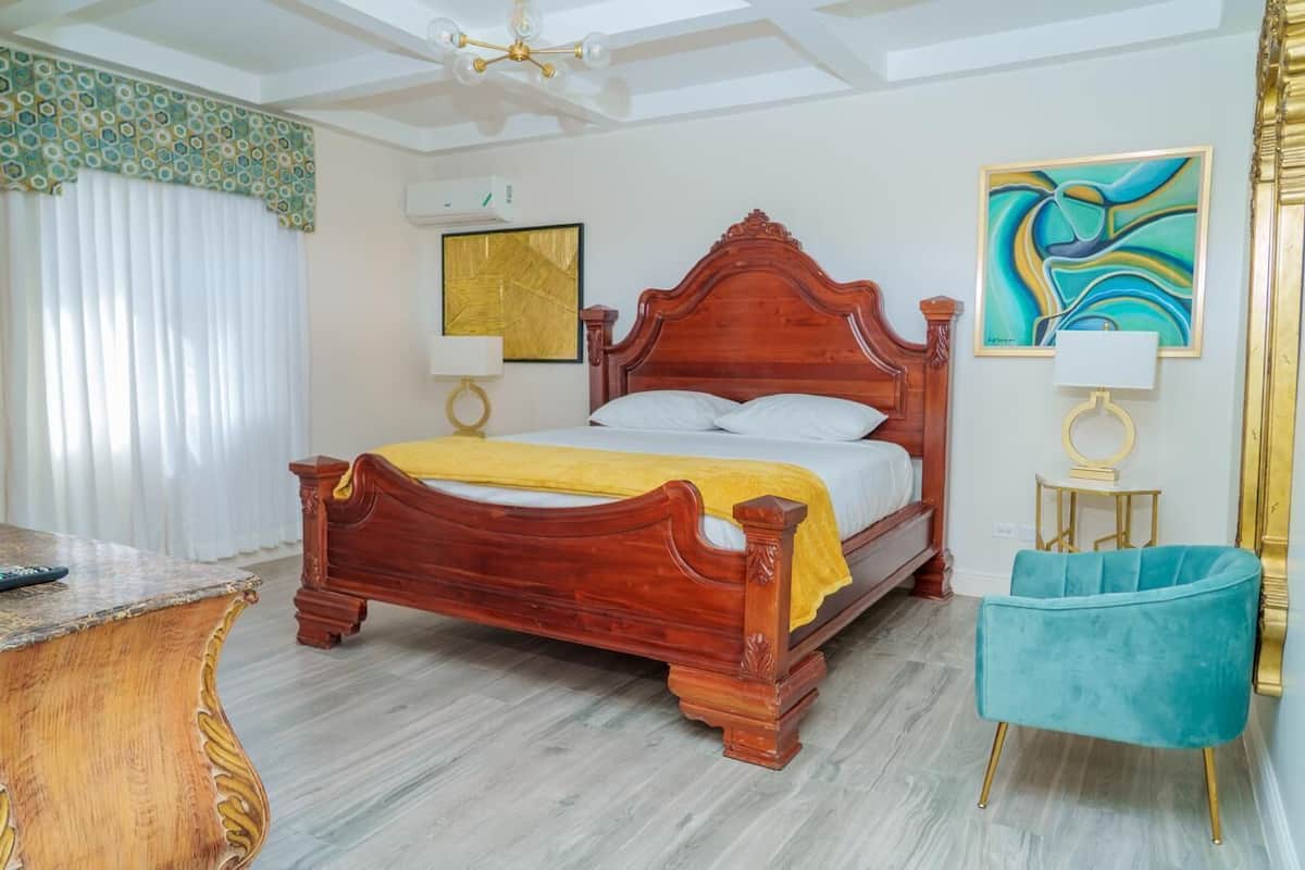A bedroom with a wooden bed, a desk, a chair, and artwork on the walls.