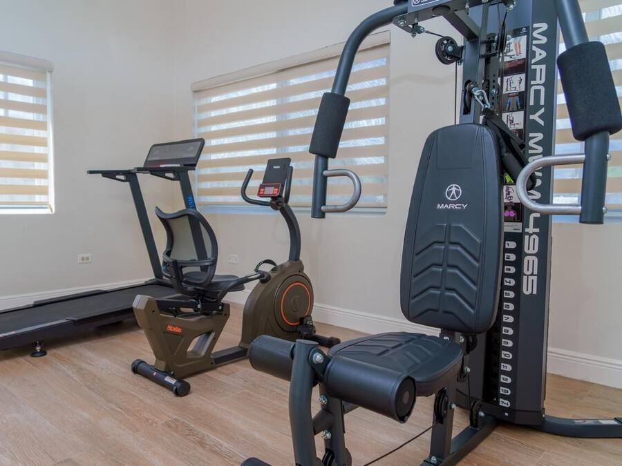Une salle de sport équipée d’un tapis de course, d’un vélo elliptique et d’un banc de musculation.