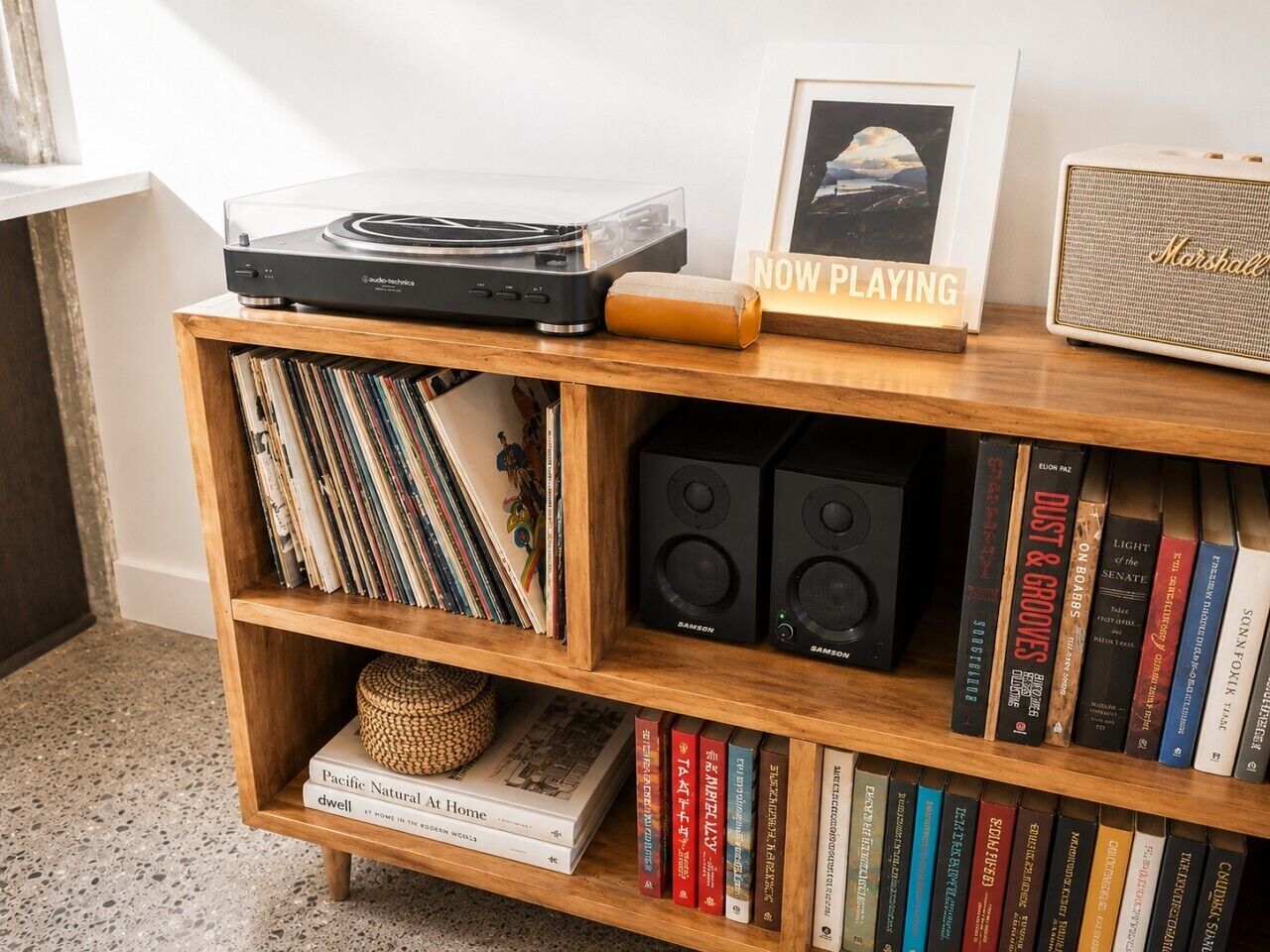 Una estantería de madera con discos de vinilo, libros y un tocadiscos.