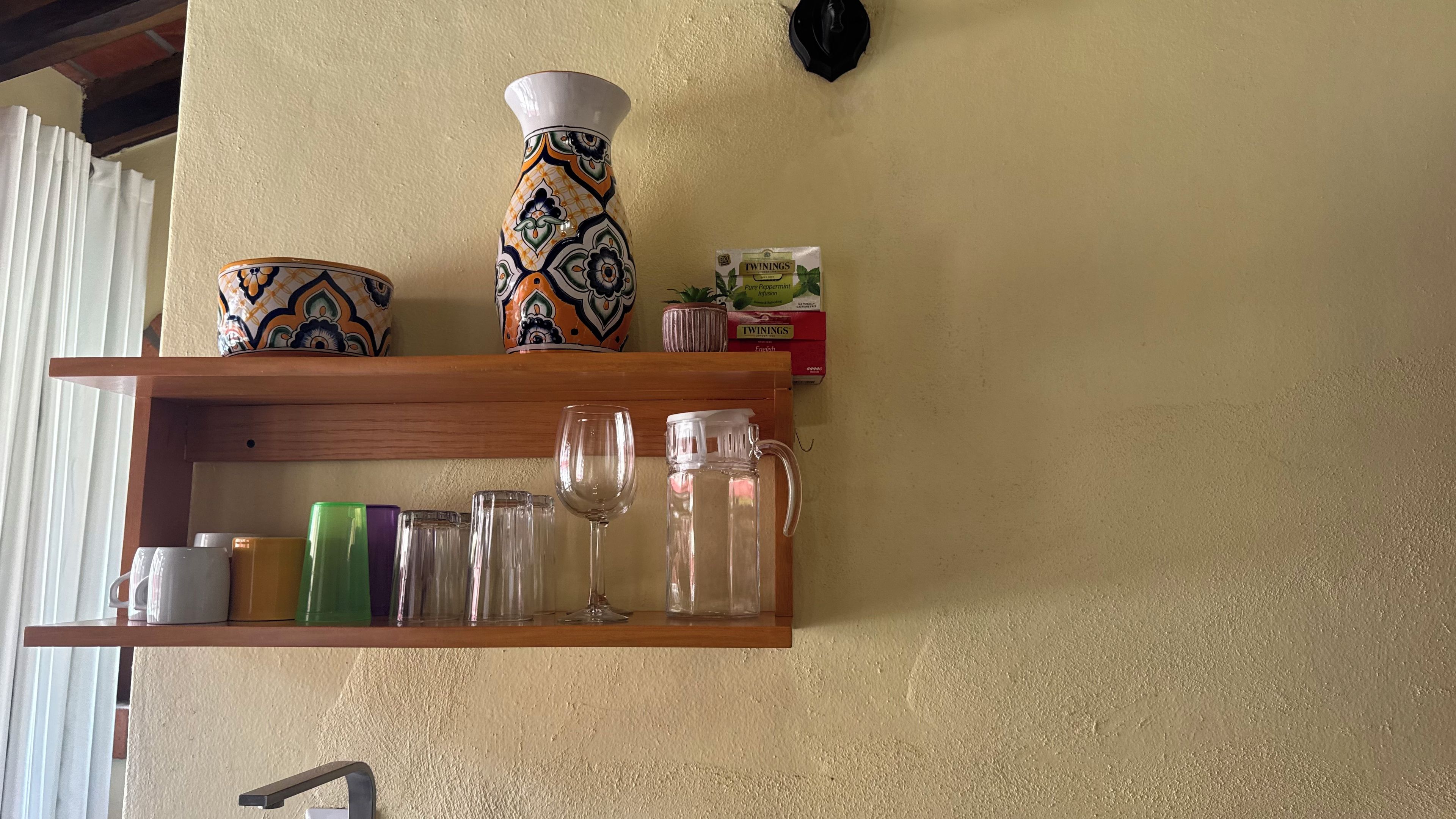A shelf with various glassware and a decorative vase.