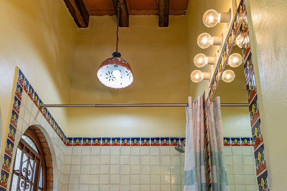 Ein Badezimmer mit gefliesten Wänden, einer Hängeleuchte und einer Duschvorhang.