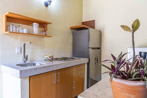 A kitchen with a stainless steel refrigerator, wooden cabinets, a granite countertop, a sink, and a potted plant. - Maito Suite - Romantic Zone (Puerto Vallarta)