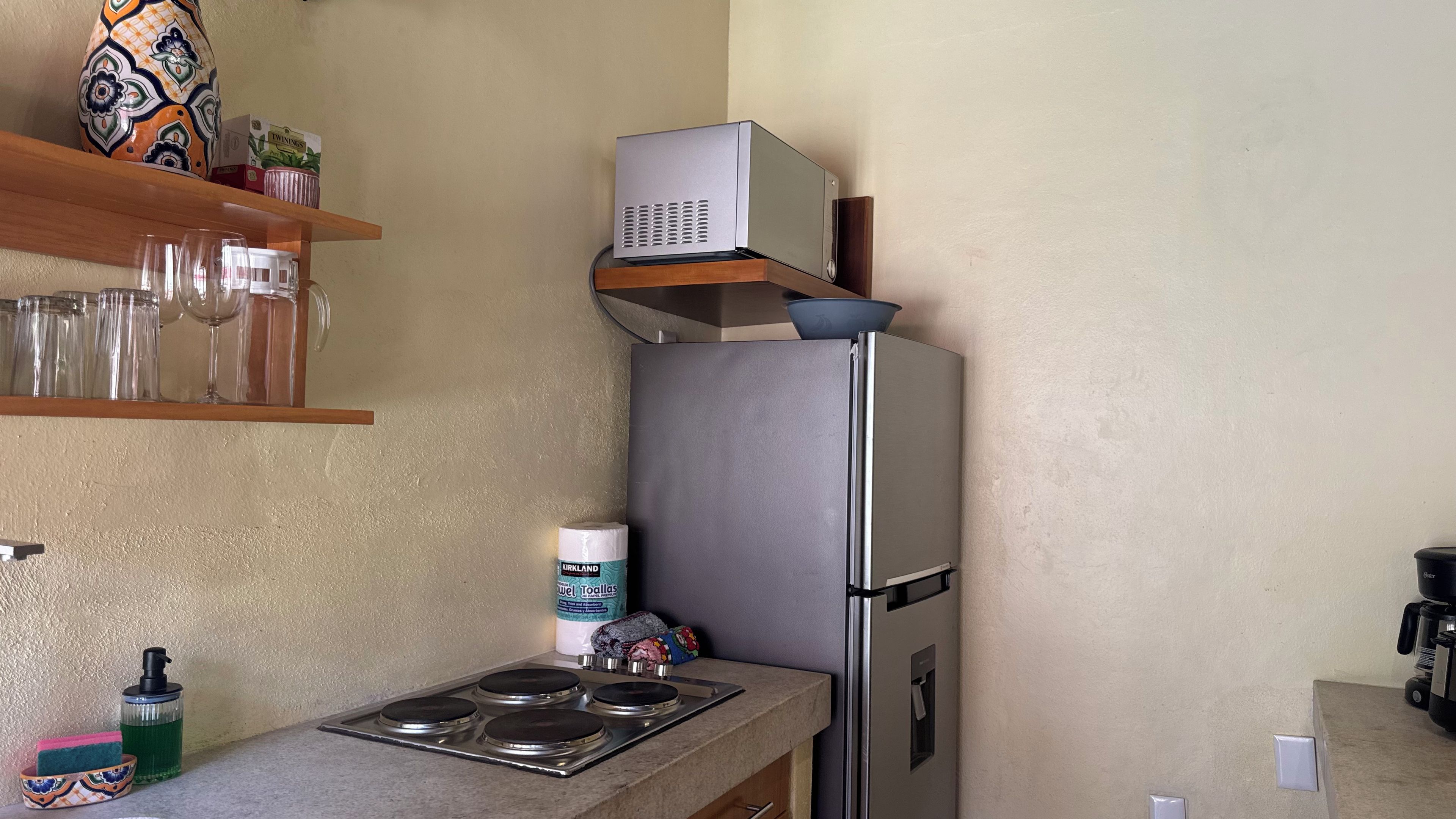 Eine kompakte Küche mit einem Edelstahl-Kühlschrank, einem eingebauten Backofen und einem kleinen Spülbecken.