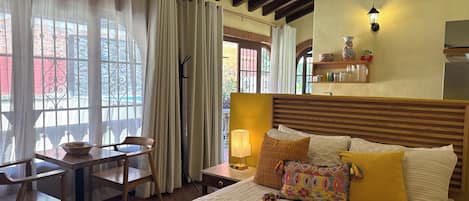 Une chambre d’hôtel avec un lit, une table et des chaises, une lampe et une vue sur l’extérieur.
